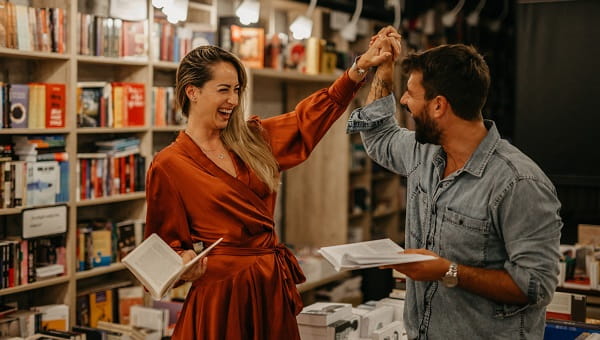 A man and a woman high five in a book shop