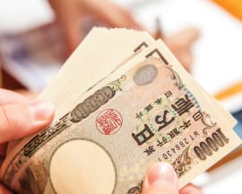 japanese yen bank notes fanned in someone's hands