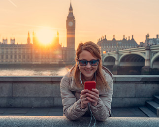 follow us on instagram, Woman smiling while texting in front of the river Thames and Big Ben in London